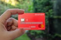 Monzo bank card hold in hand, with a green blurred background. .The sensitive info covered by stickers with the dummy digits and c