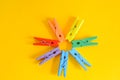 Mood-boosting color concept, colorful wooden multi-colored clothespins in the shape of a flower on a yellow paper background. Royalty Free Stock Photo