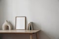 Moody artistic living room interior, home office. Empty wooden picture frame, poster mockup on wooden table. Old books