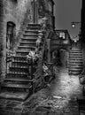 A moody black and white image of an old building and stone stairs in Civita Italy