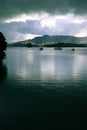 Moody changeable overcast sky in winter with sunshine on green h Royalty Free Stock Photo