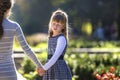 Moody cute child girl holding mother hand looking back on warm day outdoors. Family relationship and recreation Royalty Free Stock Photo