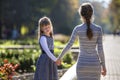 Moody cute child girl holding mother hand looking back on warm day outdoors. Family relationship and recreation Royalty Free Stock Photo