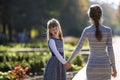 Moody cute child girl holding mother hand looking back on warm day outdoors. Family relationship and recreation Royalty Free Stock Photo