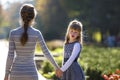 Moody cute child girl holding mother hand looking back on warm day outdoors. Family relationship and recreation Royalty Free Stock Photo