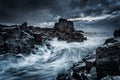 Moody dramatic skies and large waves crash onto coastal rocks