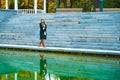 Moody girl walking in park and reflecting in lake water