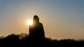 A moody, hooded figure silhouetted against the sunset. With deliberate lens flare Royalty Free Stock Photo