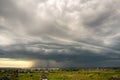 Moody landscape with dark stormy clouds with falling heavy downpour shower rain over distant town buildings in summer Royalty Free Stock Photo