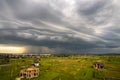 Moody landscape with dark stormy clouds with falling heavy downpour shower rain over distant town buildings in summer Royalty Free Stock Photo