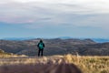 Moody low angle evening view of a young female hiker standing with the mountain landscape near the summit of Mount Kosciuszko