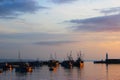 Moody Mevagissey fishing boats sunlit in the harbour, lighthouse on the quay, at sunrise. South coast of Cornwall England