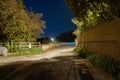 A moody night scene of a country lane lit up with a street light on a summers night