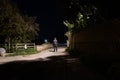 A moody night scene of a hooded man standing on a country lane lit up with a street light on a summers night Royalty Free Stock Photo