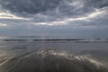 Moody ramatic sky reflected on wet beach landscape