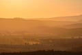 A moody sunset over a mountain range, fields shrouded in fog Royalty Free Stock Photo