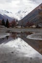 Moody swiss church in alpine region reflected in little puddle