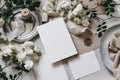 Moody wedding table mockup scene. Feminine desktop composition with fading white rose flowers, silver plate, silk
