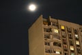 The moon on the background of a dark sky and a residential high-rise building.