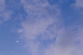 Moon behind the clouds during the day on a bright blue sky Royalty Free Stock Photo