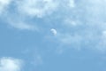 The moon in the blue sky is partially hidden by the clouds, the daytime shot. Cloudscape Royalty Free Stock Photo