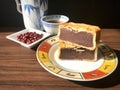 Moon cake stack together, served with tea, and some red beans in sauce dish at side, on wooden background.