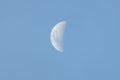 A closeup photo of a breathtaking mystical vertical half moon in a light blue sky on a sunny day Royalty Free Stock Photo