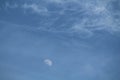 Moon and Cirrus fibratus clouds in blue daytime sky Royalty Free Stock Photo