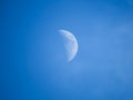 Moon during day in the blue sky between clouds.