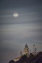 Moon eclipse over a lighthouse on the coast