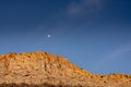 Moon Hangs In a Blue Sky Above Sunlit Orange Cliffs