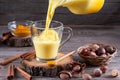 Moon milk for better sleep. Turmeric Golden milk with cinnamon. Moon milk is poured from a jug into a glass Royalty Free Stock Photo