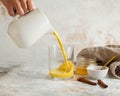 Moon milk for better sleep. Turmeric Golden milk with cinnamon. Moon milk is poured from a jug into a glass Royalty Free Stock Photo