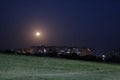 The moon on the outskirts of the city at night under the light of lanterns. night city landscape moon over grass Royalty Free Stock Photo