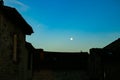 Moon over the roofs of old stone houses Royalty Free Stock Photo