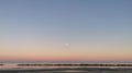 Moon over the sea in a pink and blue sunset that reflects on the waters of the Mediterranean