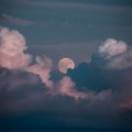 Moon peeks through billowing clouds, creating a mystical ambiance