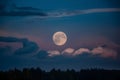 Moon peers through night sky with wisps of clouds