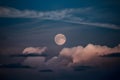 Moon peers through night sky with wisps of clouds