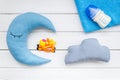 Moon pillow, clouds, baby bottle and toys for put newborn in bed on white wooden background top view