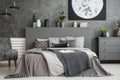 Moon poster on concrete wall above bed with bedhead in grey bedroom interior. Real photo Royalty Free Stock Photo