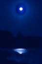 Moon reflected in the lake at night. Blue toned image. Royalty Free Stock Photo