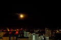 The moon rises above the lights of the night city. Time Lapse Royalty Free Stock Photo