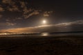 A moon rising above the surface of the ocean that throws reflections on the water levels captured during the strong wind in the Royalty Free Stock Photo