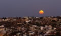 Moon rising over coastal town and homes, super moo