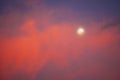 The moon set behind colorful red clouds at sunset Royalty Free Stock Photo