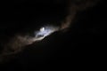 Moon shines behind the clouds at the dark night sky, background Royalty Free Stock Photo