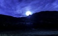 A moon is shining brightly in the sky above a mountain range Royalty Free Stock Photo