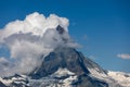 Moon shining over the famous matterhorn with clouds and blue sky