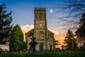 Moon in the sky at sunset behind church clock tower in Corsley, Wiltshire, UK Royalty Free Stock Photo